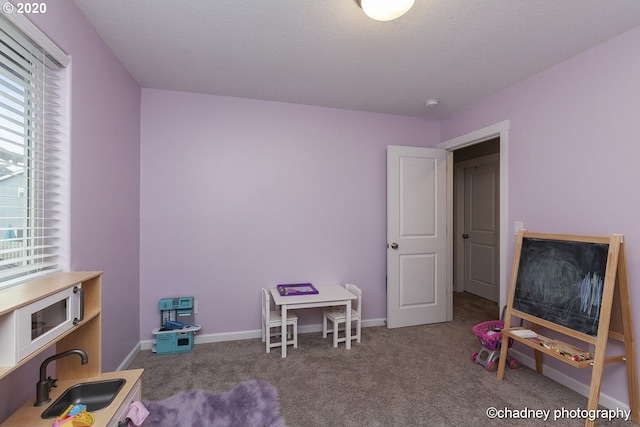 game room featuring a sink, a textured ceiling, carpet flooring, and baseboards