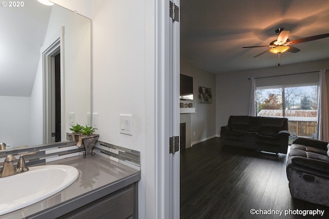 bathroom with ceiling fan, a fireplace, wood finished floors, and vanity