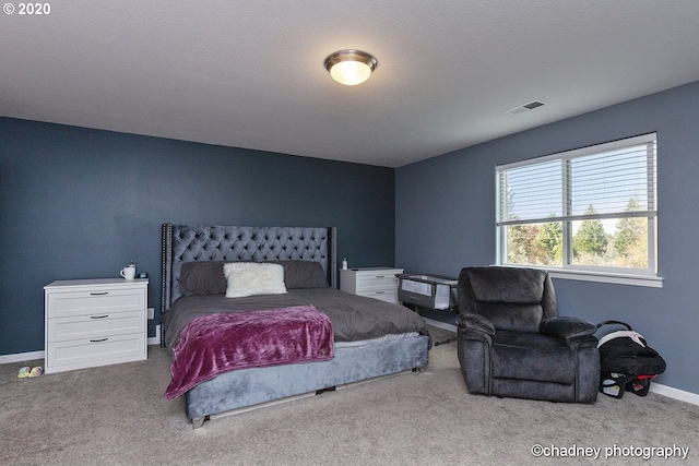 bedroom with baseboards, a textured ceiling, visible vents, and light colored carpet