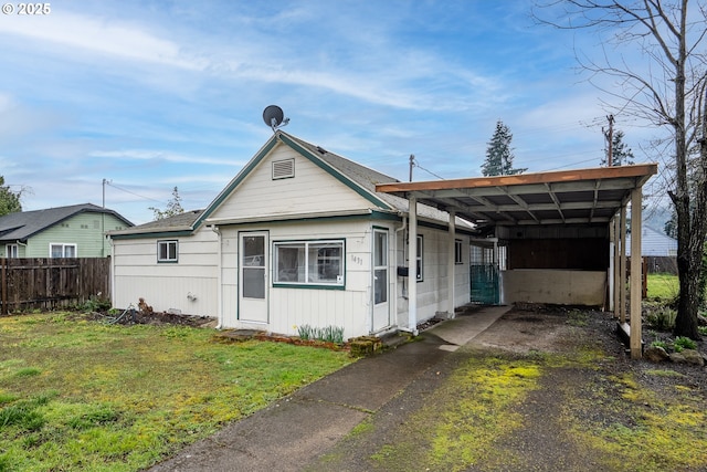 view of front of property with a front yard, fence, driveway, and a carport