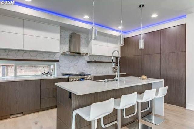 15 Hood St, Camas, WA 98607 - kitchen featuring wall chimney exhaust hood, modern cabinets, light wood-type flooring, a breakfast bar, and recessed lighting