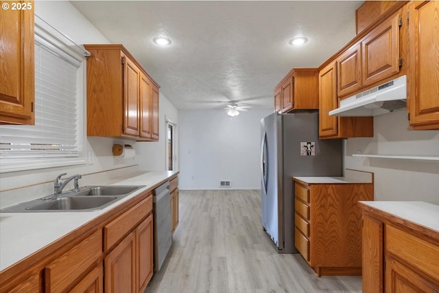 kitchen featuring a sink, under cabinet range hood, brown cabinets, ceiling fan, and light countertops