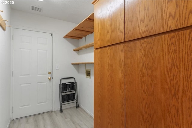 clothes washing area with washer hookup, light wood finished floors, and baseboards