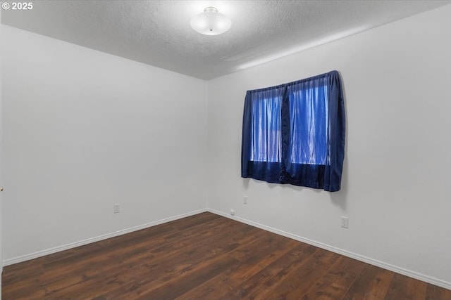 empty room featuring wood finished floors, a textured ceiling, and baseboards