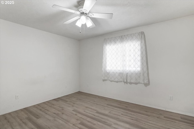 empty room featuring wood finished floors, a ceiling fan, and baseboards