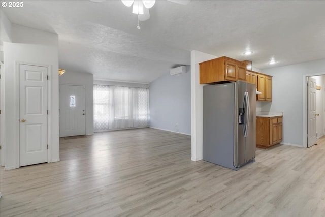 kitchen with stainless steel fridge, a wall mounted air conditioner, a ceiling fan, light wood-style floors, and open floor plan