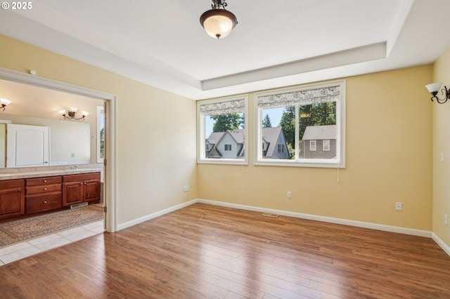 1145 NW 22nd Ave, Camas, WA 98607 - unfurnished bedroom featuring light wood-style floors, a tray ceiling, baseboards, a sink, and connected bathroom