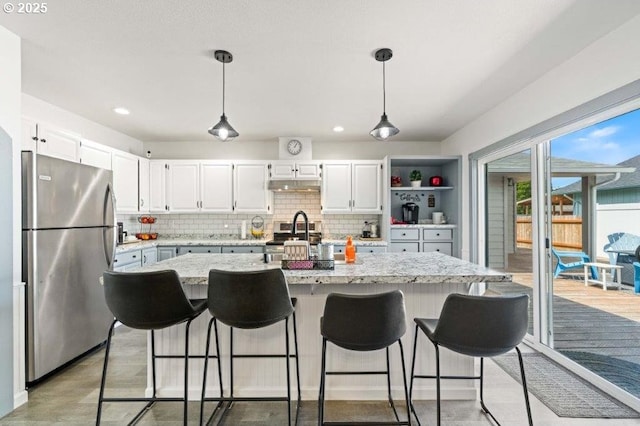 3060 Pine St, North Bend, OR 97459 - kitchen with freestanding refrigerator, under cabinet range hood, decorative backsplash, white cabinets, and recessed lighting