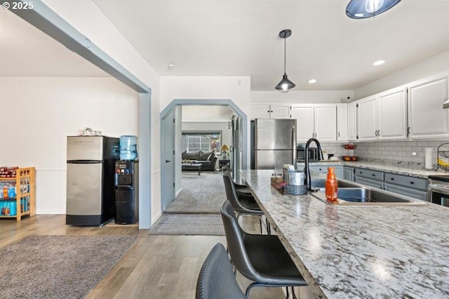 3060 Pine St, North Bend, OR 97459 - kitchen featuring freestanding refrigerator, light wood-type flooring, white cabinets, arched walkways, and recessed lighting