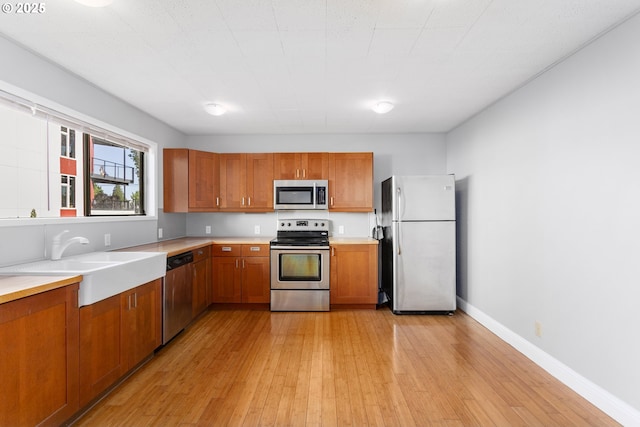 2125 NE 48th Ave, Portland, OR 97213 - kitchen with appliances with stainless steel finishes, a sink, brown cabinets, and light wood-style flooring
