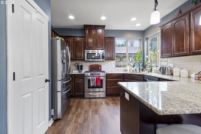 4219 NE 157th Ct, Vancouver, WA 98682 - kitchen featuring a peninsula, appliances with stainless steel finishes, dark wood-style flooring, a sink, and backsplash