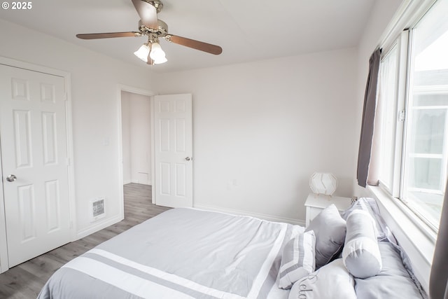 bedroom with multiple windows, wood finished floors, ceiling fan, and baseboards