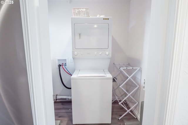 laundry area with estacked washer and dryer and wood finished floors