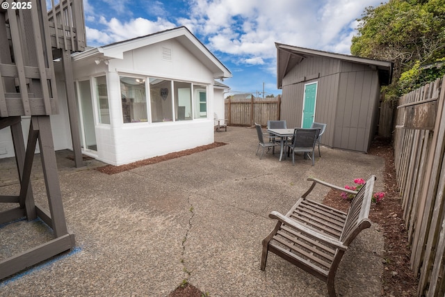 back of house with a patio area, a fenced backyard, outdoor dining space, and an outdoor structure