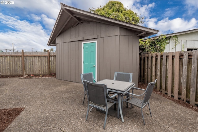 view of patio / terrace with a fenced backyard, outdoor dining area, and an outbuilding