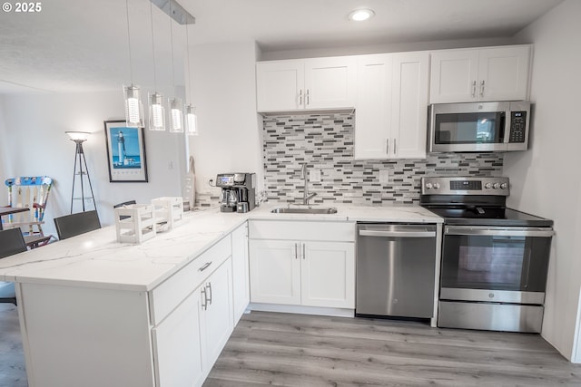 kitchen featuring stainless steel appliances, a sink, a peninsula, white cabinets, and recessed lighting