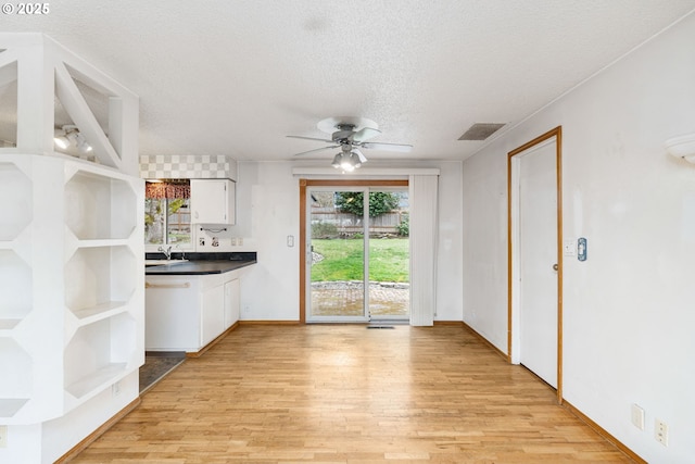 kitchen featuring open shelves, light wood-style flooring, dark countertops, and visible vents