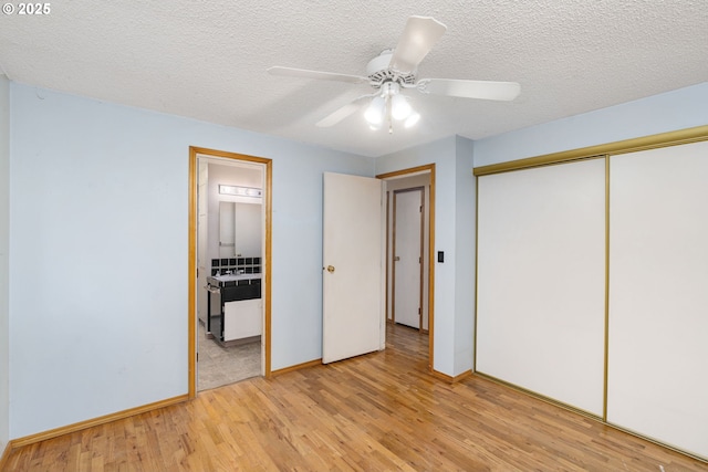 unfurnished bedroom with connected bathroom, a closet, light wood finished floors, and a textured ceiling