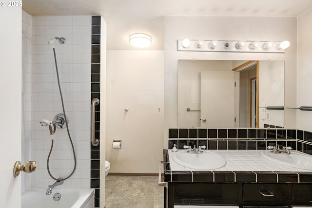 bathroom featuring double vanity, toilet, baseboards, and a sink