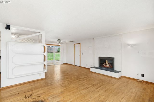 unfurnished living room with baseboards, ceiling fan, a fireplace, a textured ceiling, and wood-type flooring