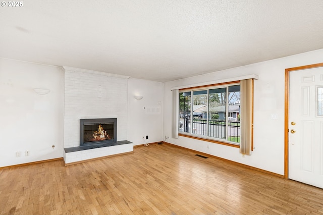 unfurnished living room with wood finished floors, a fireplace, visible vents, and baseboards