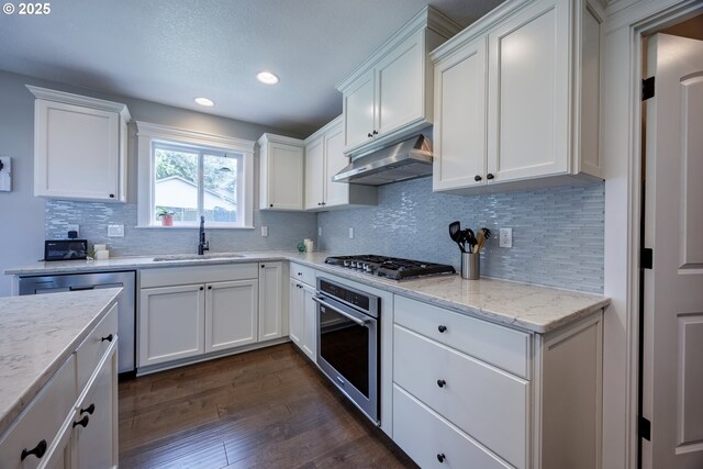 1852 SE Oar Dr, Lincoln City, OR 97367 - kitchen featuring stainless steel appliances, a sink, under cabinet range hood, dark wood-type flooring, and white cabinets