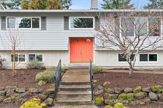 view of front of house featuring a chimney and brick siding