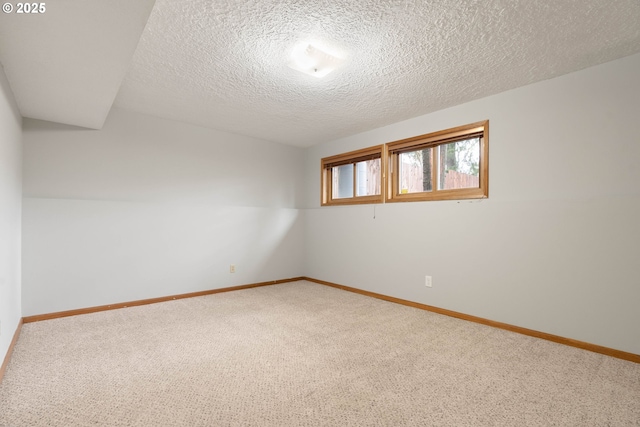 carpeted spare room with a textured ceiling and baseboards