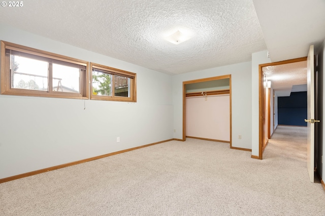 unfurnished bedroom featuring a closet, light carpet, a textured ceiling, and baseboards