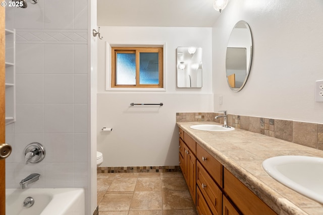 bathroom featuring double vanity, a sink, toilet, and baseboards