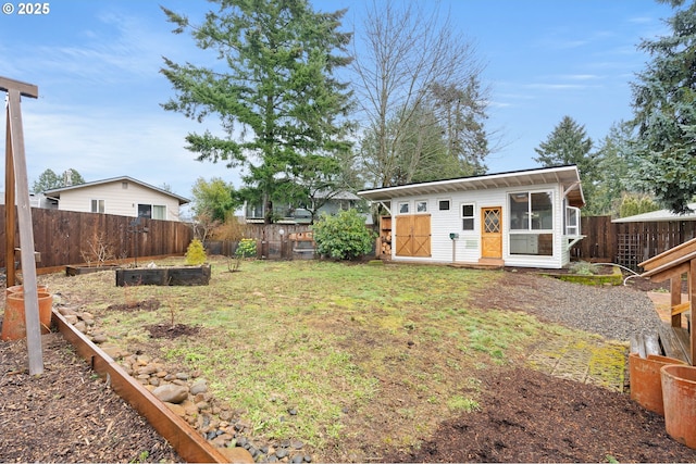 view of yard with an outdoor structure, a fenced backyard, and a garden