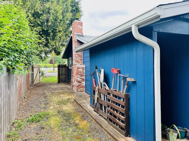 view of home's exterior with a chimney and fence