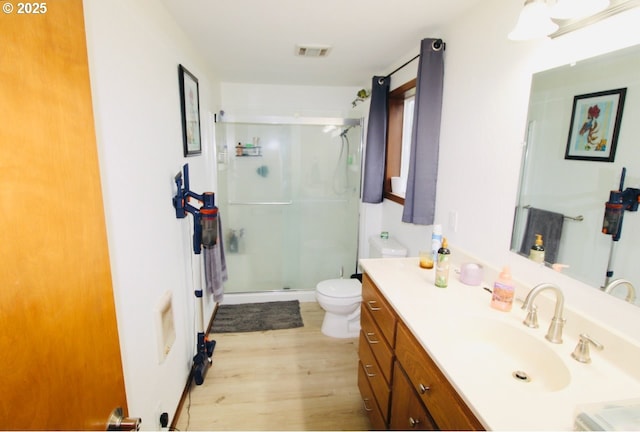 full bath featuring a stall shower, wood finished floors, toilet, and vanity