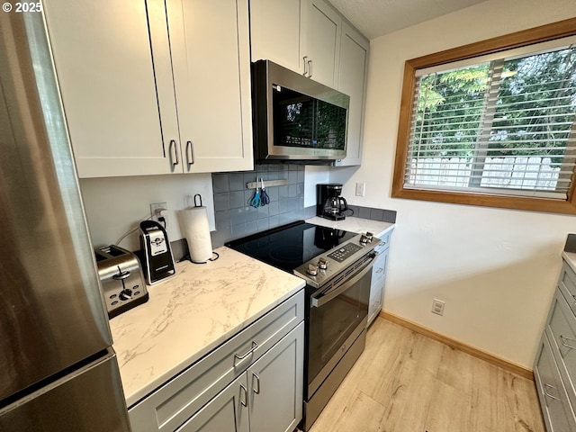 38434 Mckenzie Hwy, Springfield, OR 97478 - kitchen featuring appliances with stainless steel finishes, light wood-type flooring, decorative backsplash, light stone countertops, and baseboards