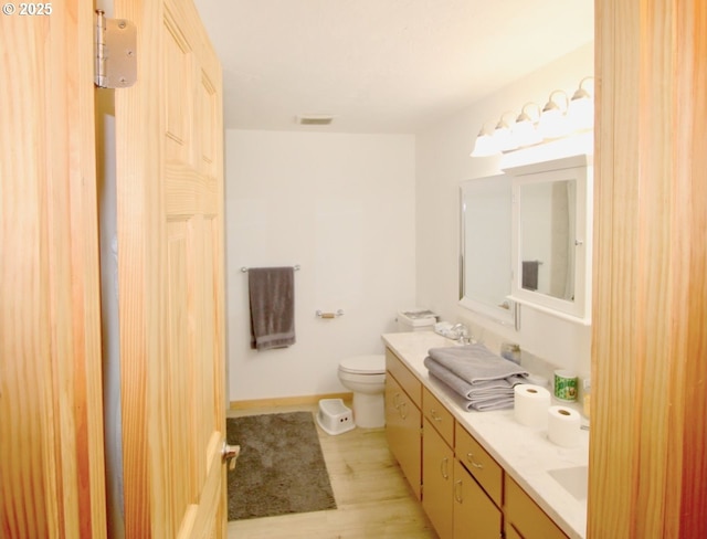 full bathroom featuring toilet, double vanity, wood finished floors, and baseboards