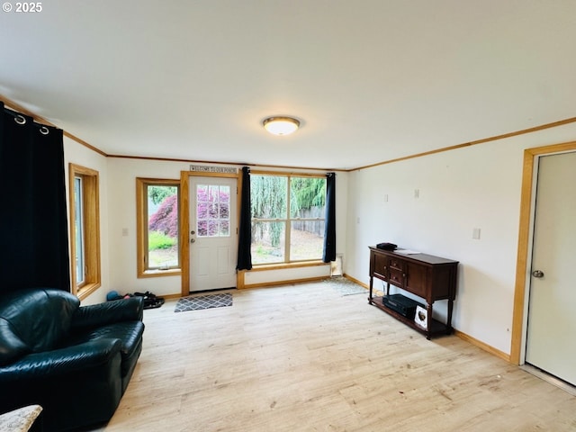 living area featuring light wood-style flooring, healthy amount of natural light, baseboards, and crown molding