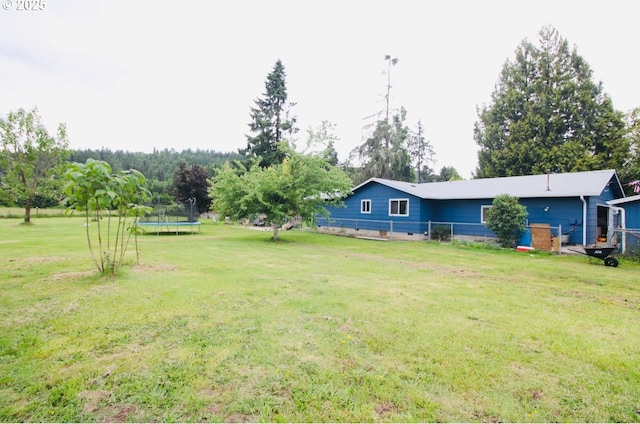 view of grassy yard featuring a trampoline