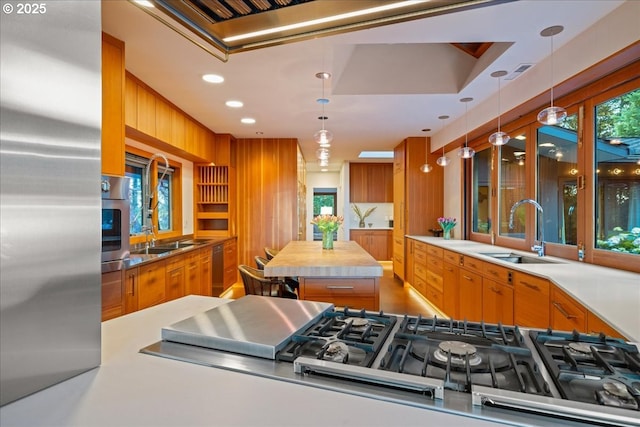 321 NW Hilltop Dr, Portland, OR 97210 - kitchen featuring a sink, stainless steel appliances, brown cabinetry, light countertops, and decorative light fixtures