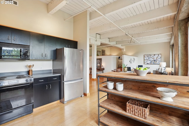 416 NW 13th Ave Unit 312, Portland, OR 97209 - kitchen with black microwave, electric range oven, freestanding refrigerator, dark cabinets, and wood ceiling with exposed beams