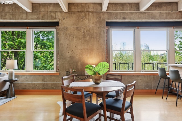 dining room with hardwood / wood-style floors, beamed ceiling, and plenty of natural light