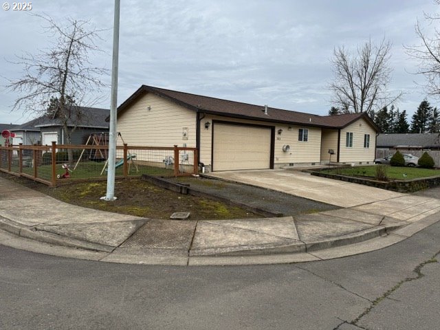 ranch-style house with driveway, an attached garage, and fence