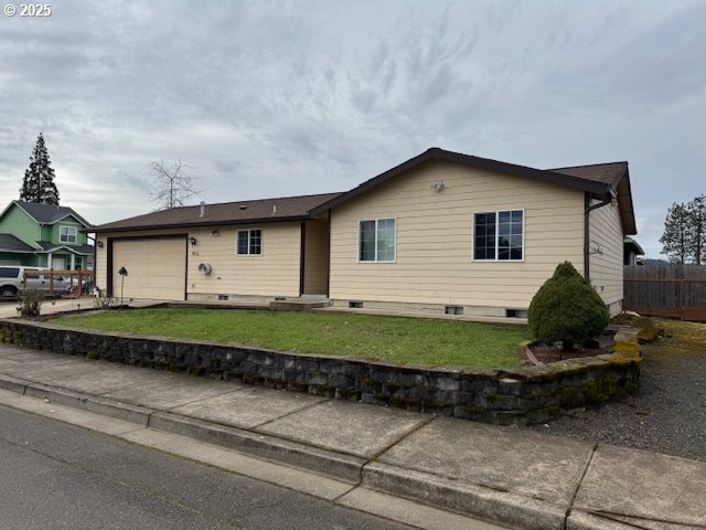 ranch-style house with an attached garage, driveway, fence, and a front lawn