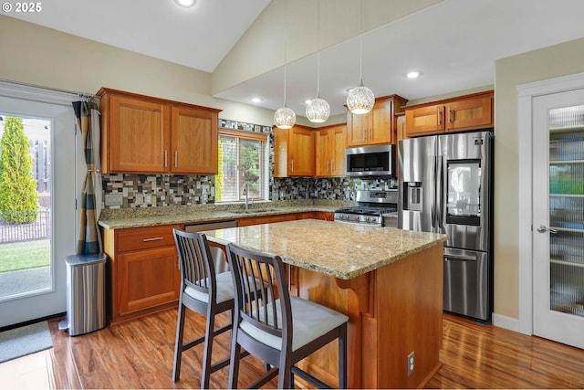 kitchen featuring backsplash, stainless steel appliances, vaulted ceiling, and a sink