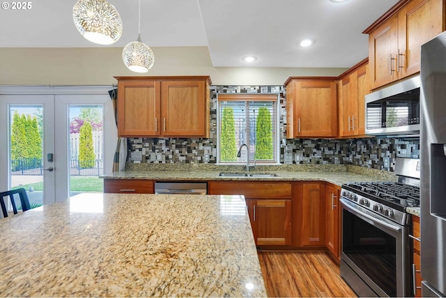 kitchen with tasteful backsplash, light stone countertops, brown cabinets, a sink, and stainless steel appliances