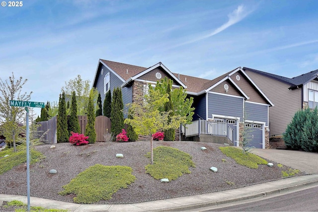 view of front of house featuring an attached garage, fence, stone siding, and aphalt driveway