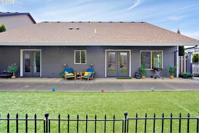 back of property featuring fence, a shingled roof, a patio area, french doors, and a lawn