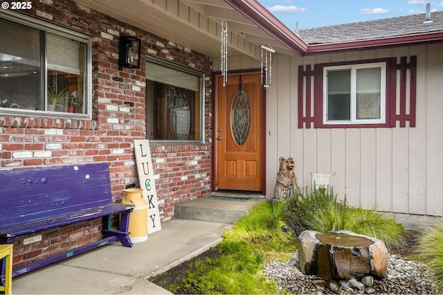 property entrance featuring brick siding and a shingled roof