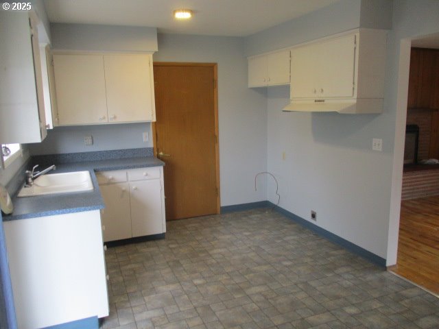 1210 Alder St, Elgin, OR 97827 - kitchen with white cabinetry, baseboards, and a sink