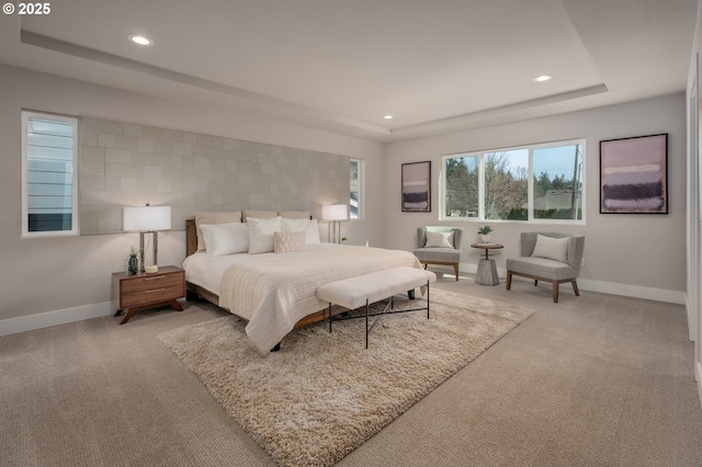 bedroom featuring a raised ceiling and light carpet