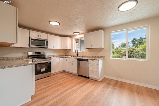 823 20th St, Springfield, OR 97477 - kitchen featuring appliances with stainless steel finishes, a textured ceiling, light wood-style flooring, and white cabinetry